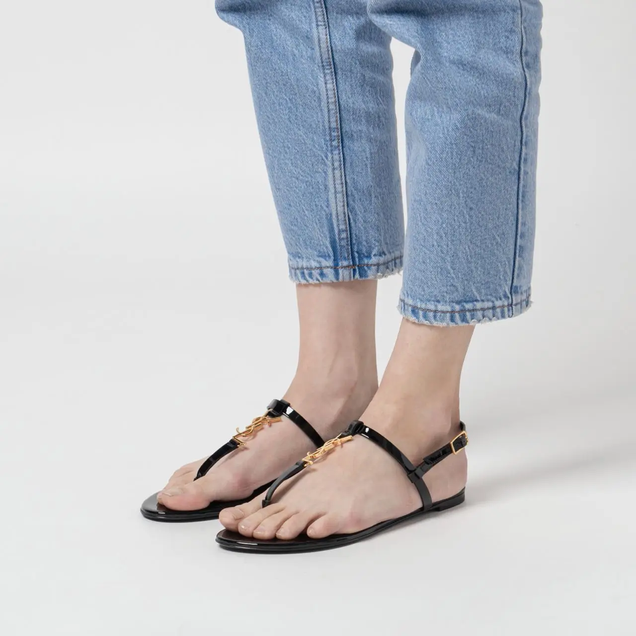 サンダル・ミュール [ SAINT LAURENT]PATENT LEATHER CASSANDRA FLAT SANDALS Saint Laurent Cassandra Leather Flat Sandals in Nero | FWRD